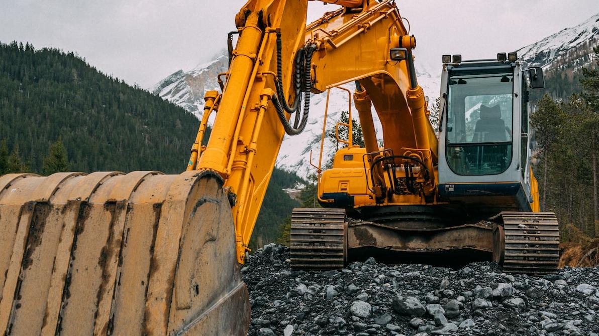 yellow and black excavator on rocky ground